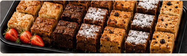 Brownies, flapjacks and iced traybakes cut into squares on a black tray